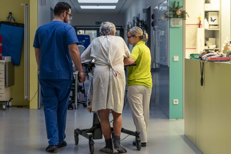 Patient läuft gestützt von Georg Steinmetz und seiner Kollegin